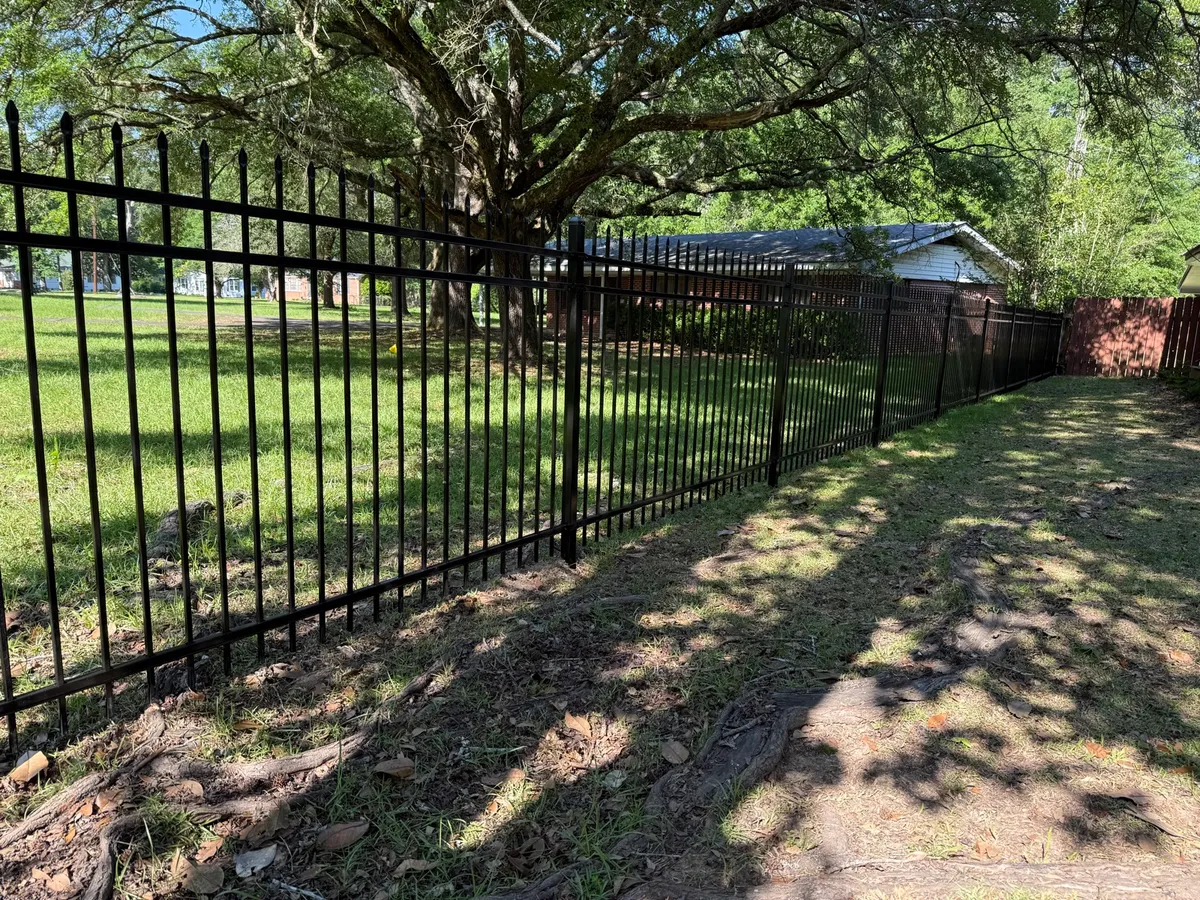 Black spear-top ornamental fence along a shaded yard
