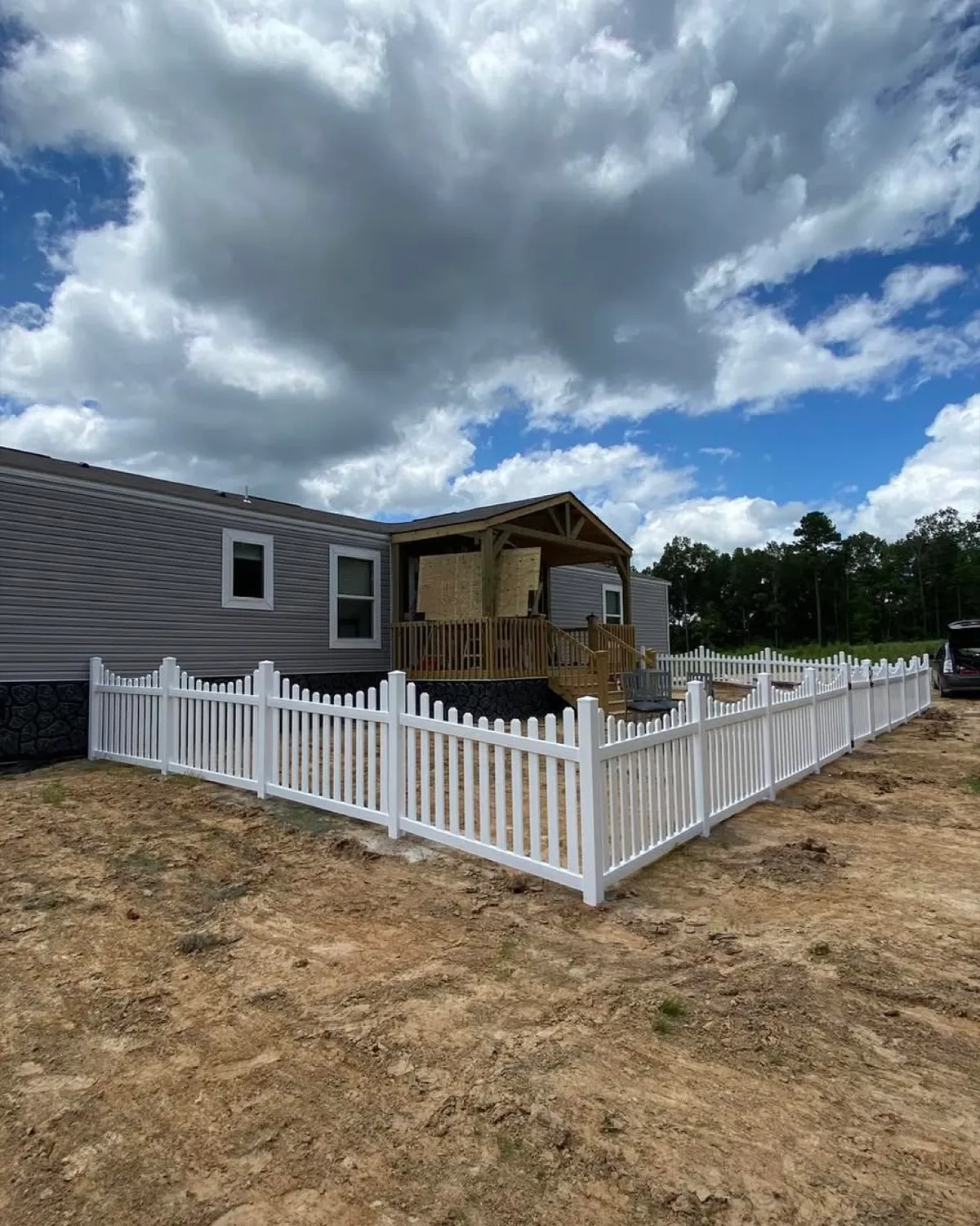 White vinyl picket fence installed around a new home