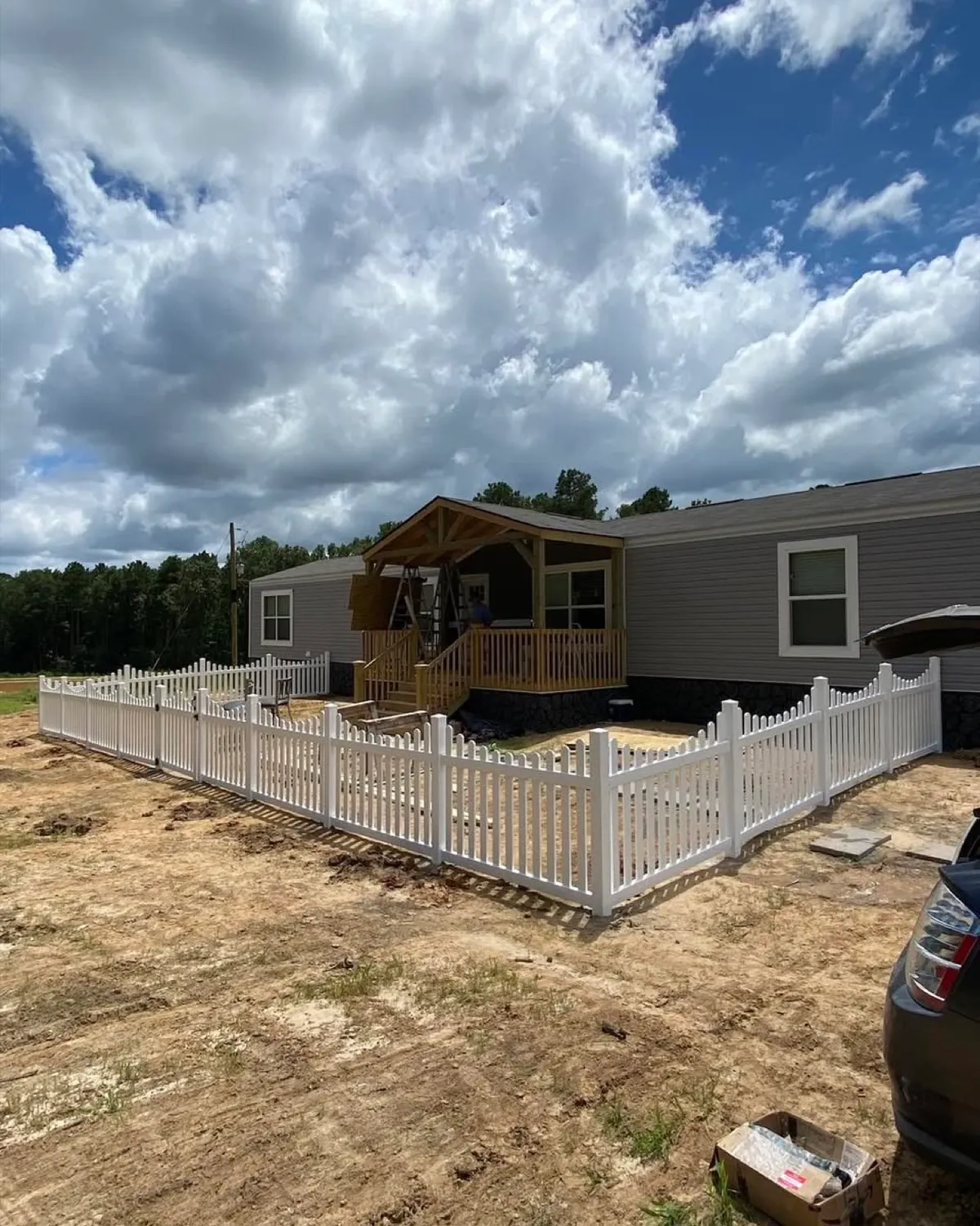 Scalloped white vinyl picket fence enclosing a new build