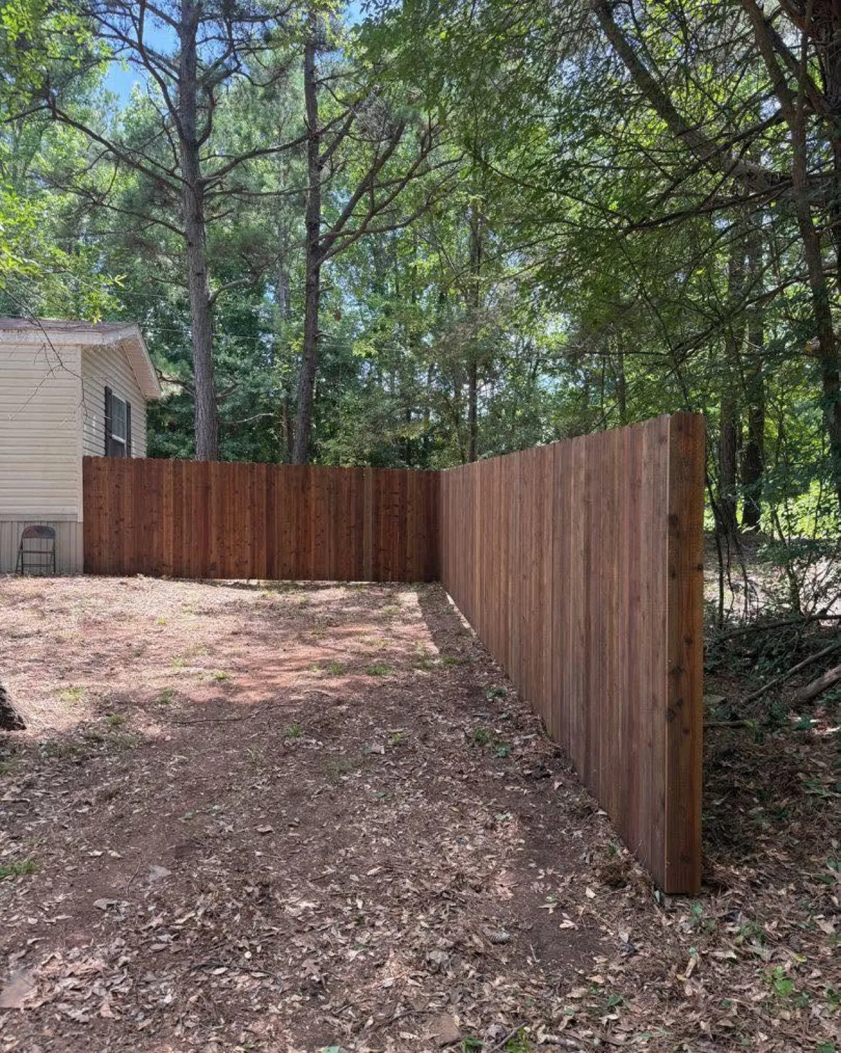Pre-stained wood privacy fence wrapping a wooded backyard